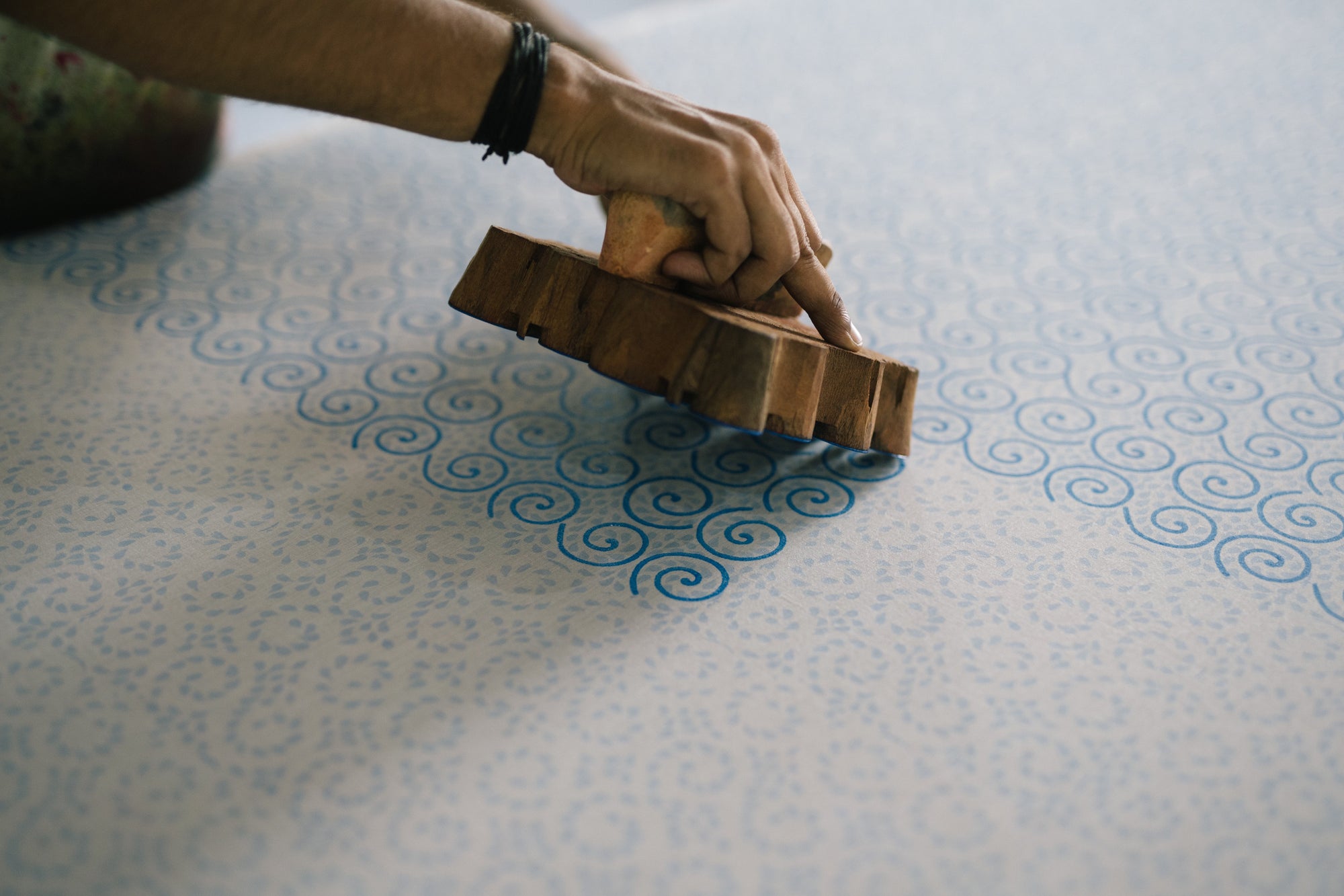 Person using a wooden brush on a textured fabric surface