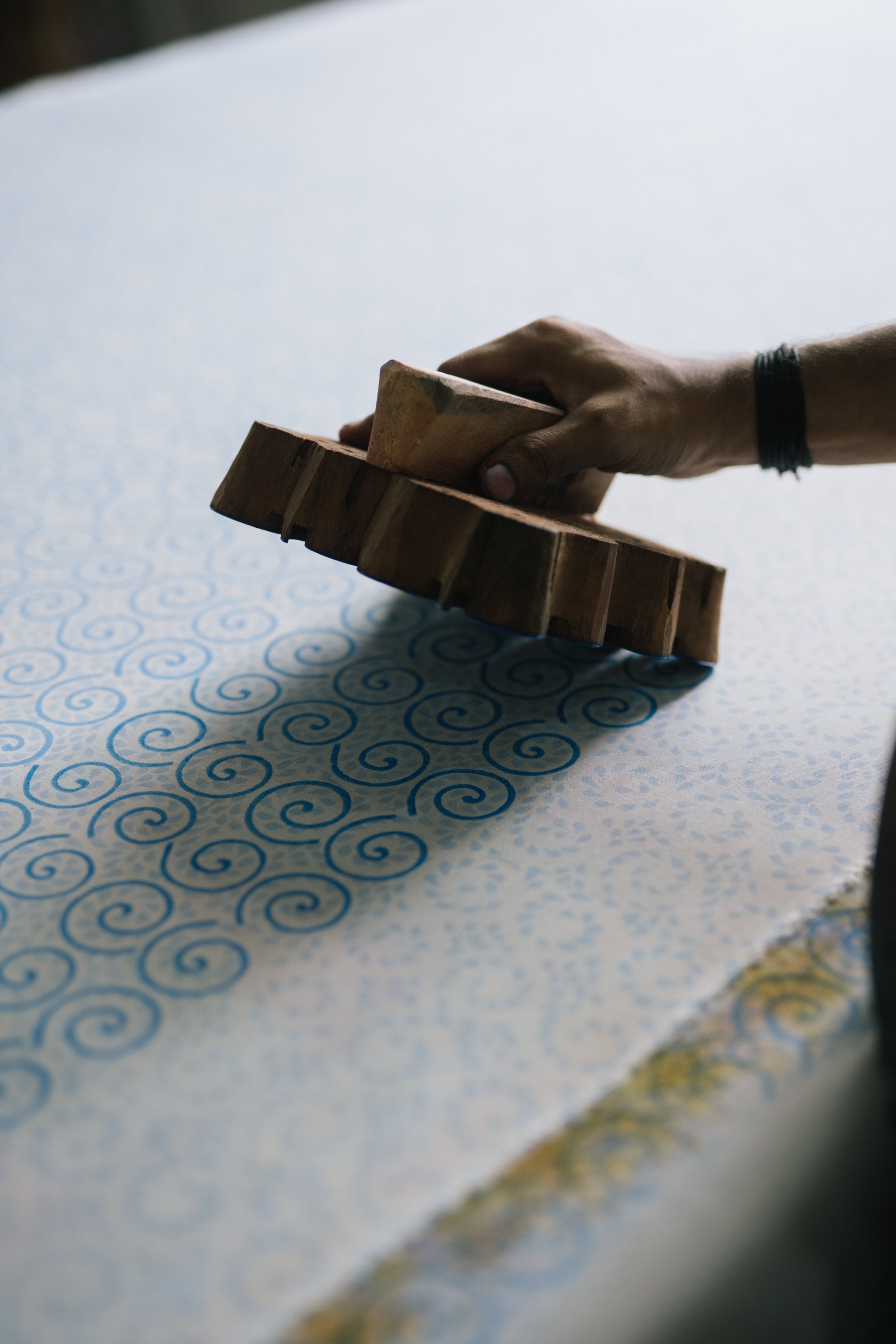 Person holding a wooden block with a pattern on a table