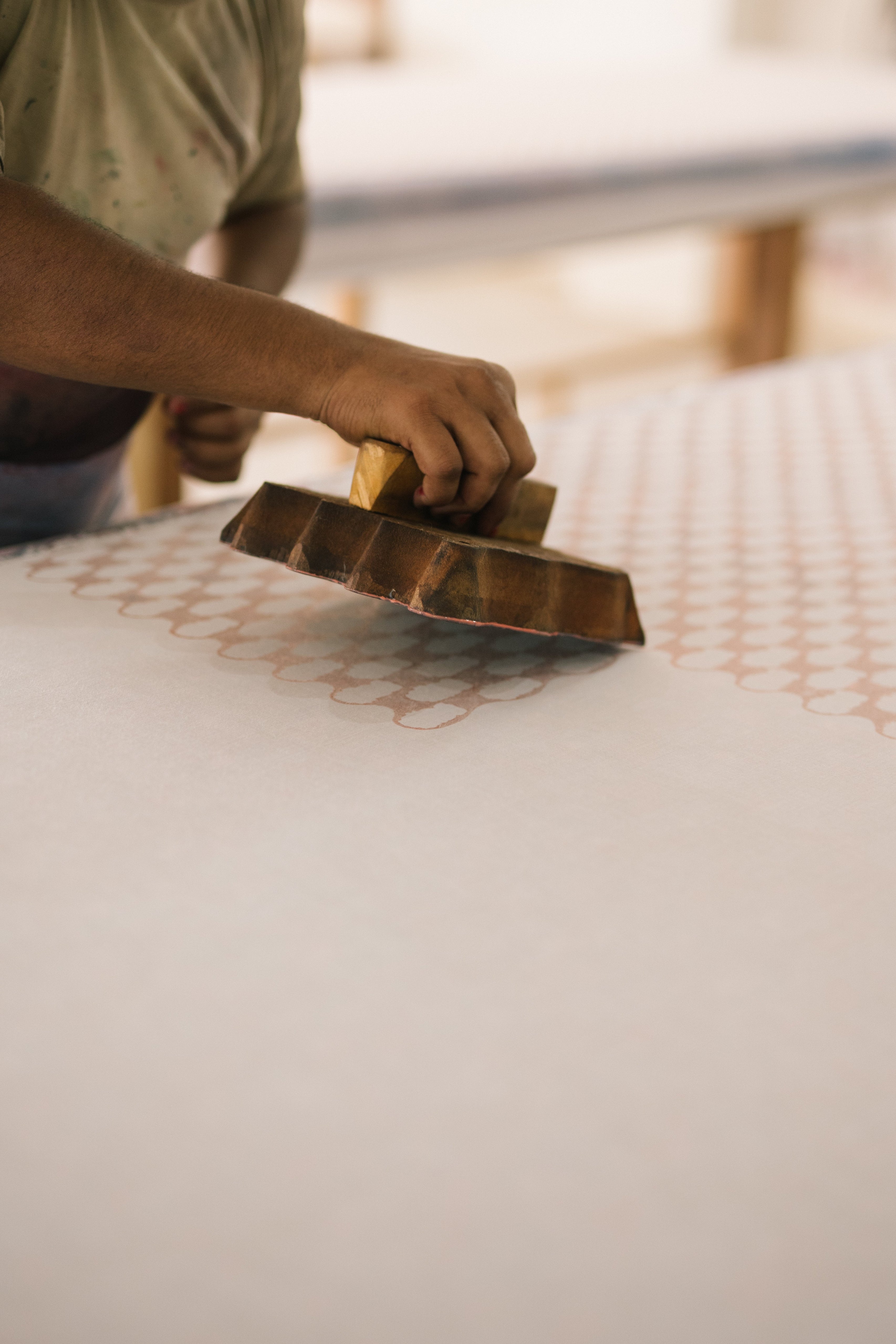 Person using a wooden tool on a mattress surface