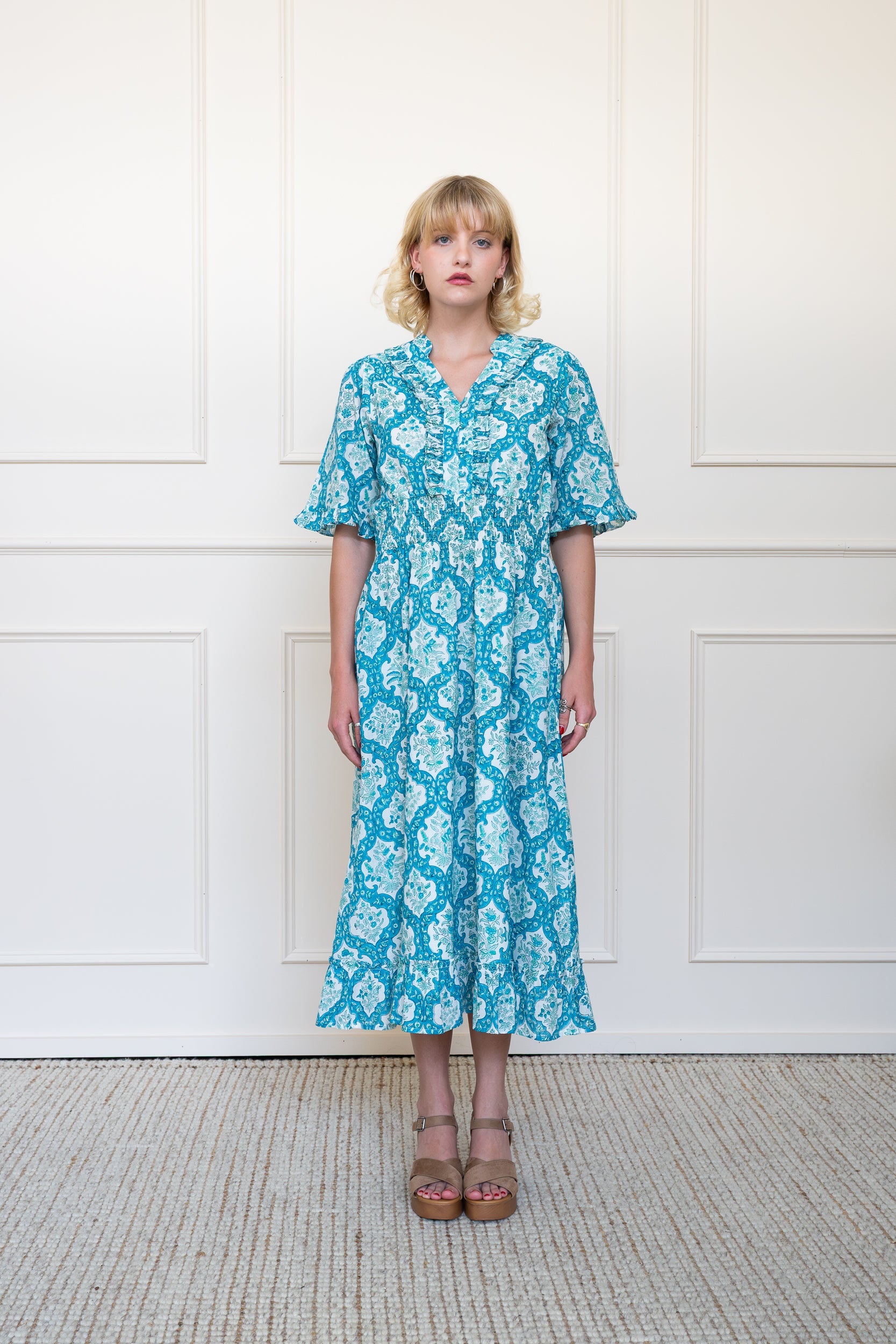 Full length front view of Airlie Dress in blue floral print showing relaxed fit midi length and tie neckline.