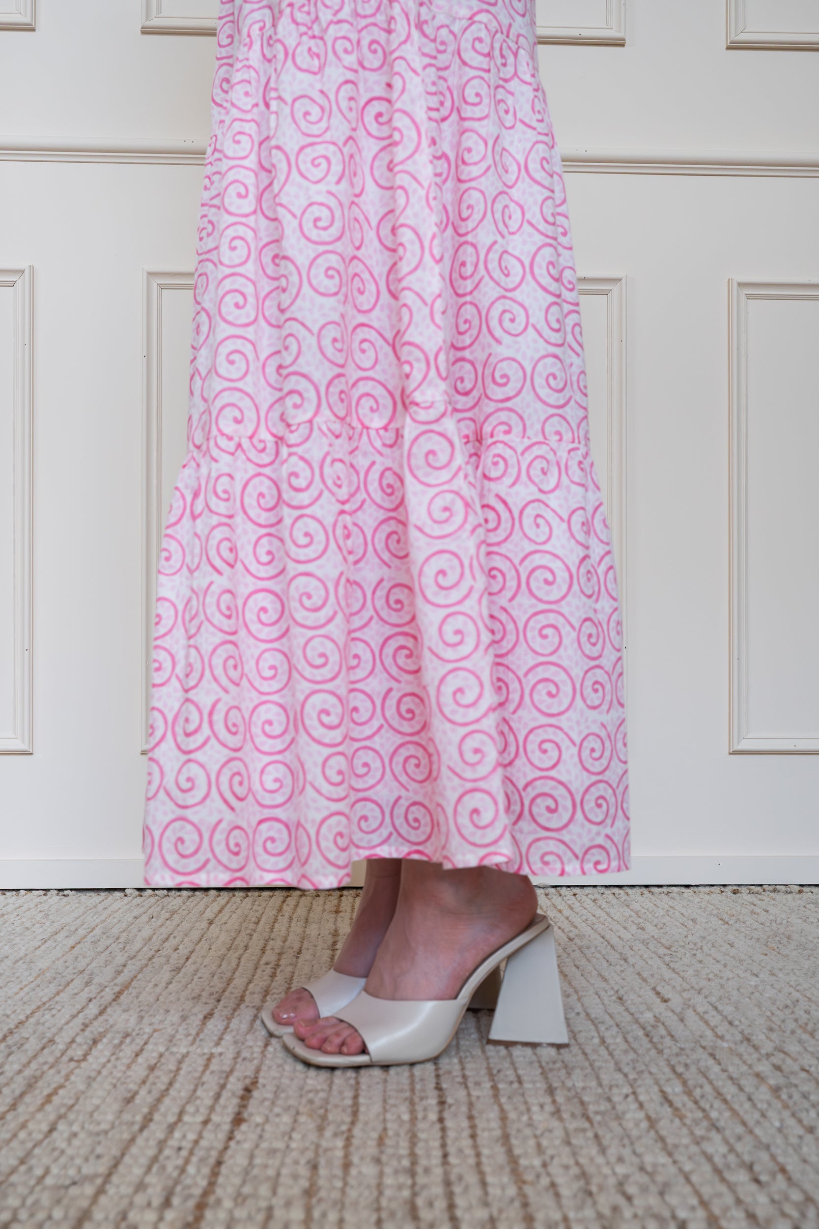 Close up of tiered skirt on Byron Bay Dress in Desert Rose pink showing maxi length styled with heels and floral pattern.