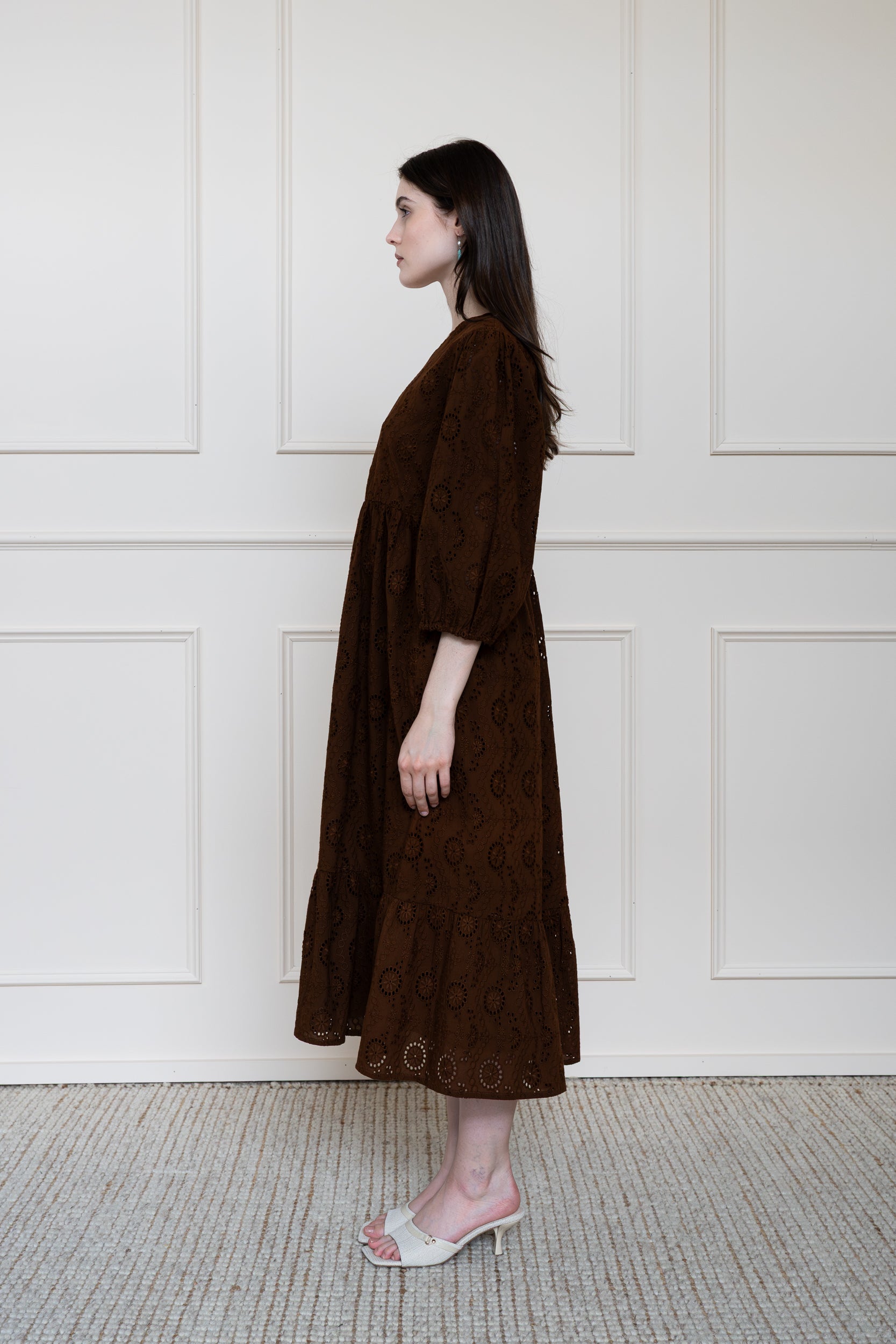 Profile view of Tamarind Dress in Brown showing textured schiffli embroidery pattern and tiered skirt shape.
