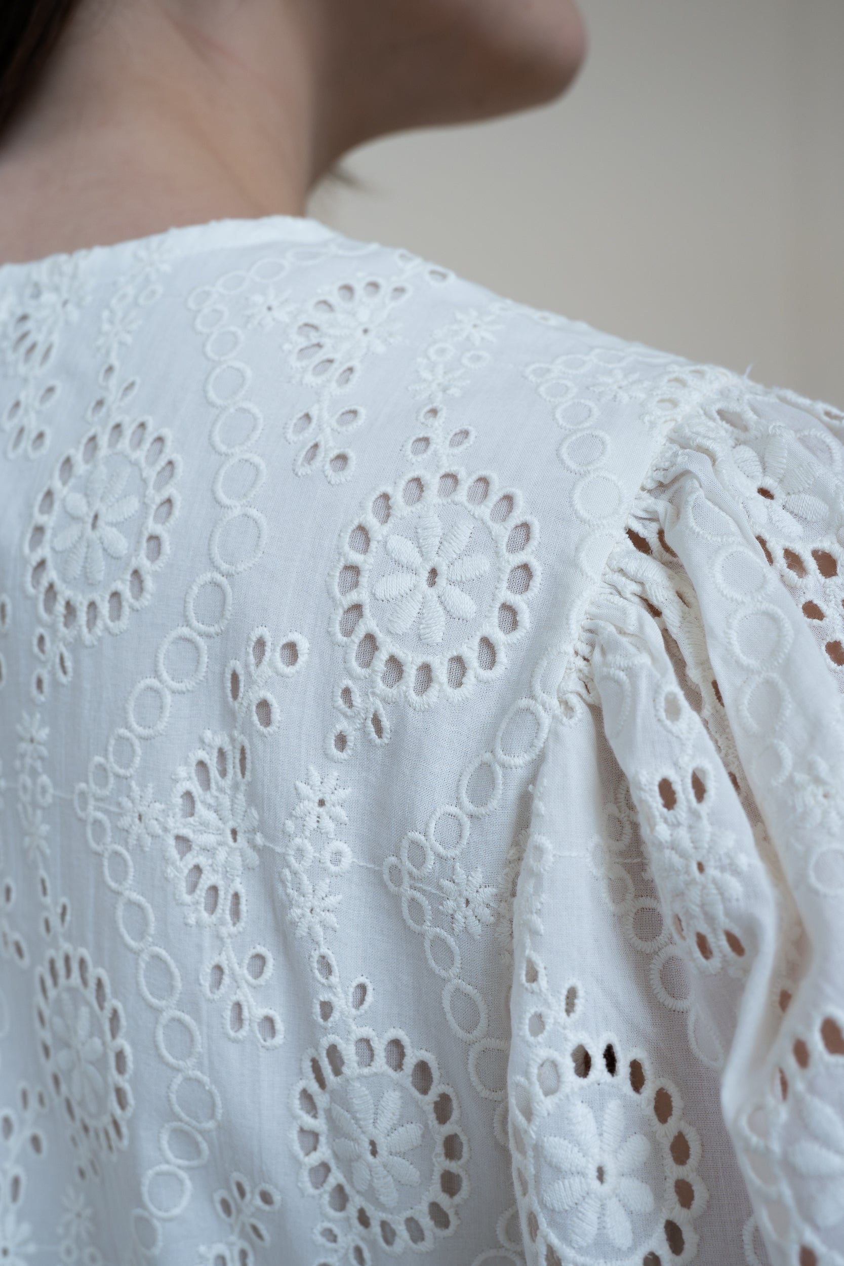 Close up back view of Tamarind Dress showing intricate schiffli embroidery detail and white organic cotton fabric.