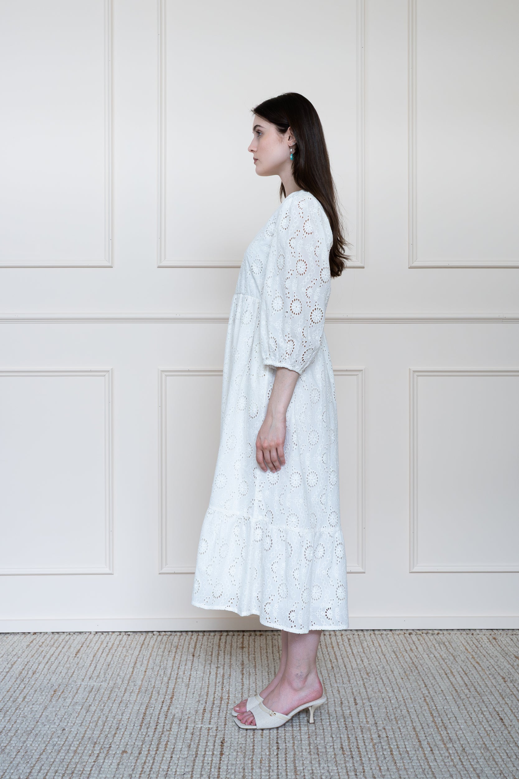 Profile view of Tamarind Dress in White showing textured schiffli embroidery pattern and tiered skirt shape.